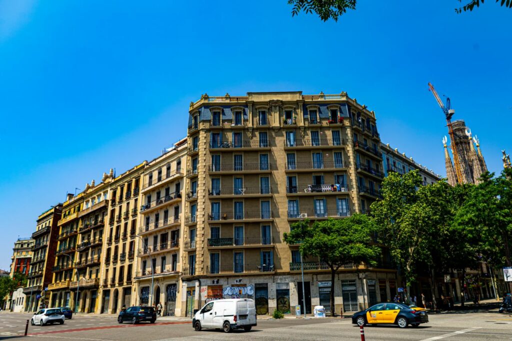 Street view of classic Barcelona architecture with the Sagrada Familia visible in summer.