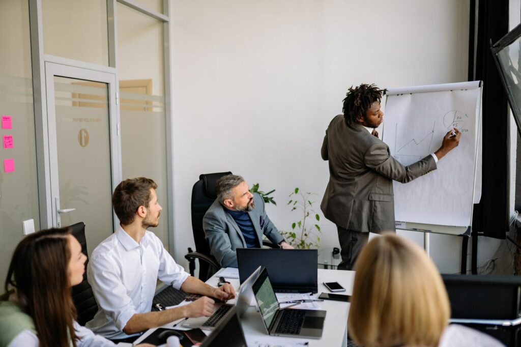 A diverse team in a modern office engaged in a strategic business meeting led by a presenter.
